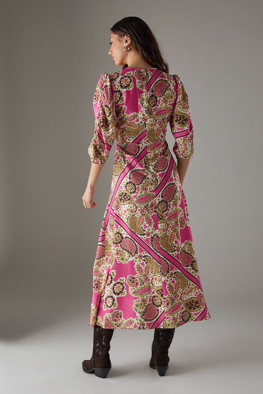 Striking paisley print midi dress with elegant V-neckline
        Feminine puff sleeves with three-quarter length for a flattering silhouette
        Flowing viscose fabric that drapes beautifully around the body
        Midi length design perfect for versatile styling options
        Subtle waist definition that enhances the feminine shape
    
    This Warehouse paisley midi dress captures confident femininity with its bold print and flattering cut. The V-neckline frames the dcolletage beautifully, while the puff sleeves add a touch of romantic charm to this contemporary piece. Style with western boots for an edgy daytime look as shown, or switch to flat sandals for relaxed weekend brunches. The flowing viscose fabric moves gracefully with every step, making it ideal for family gatherings or casual social events. For cooler days, layer with a cropped denim jacket and add statement earrings to complement the distinctive pattern. This versatile dress transitions effortlessly from day to evening - simply swap your casual footwear for block heels and add a clutch bag for dinner dates. The midi length offers the perfect balance of comfort and style for the modern British woman.