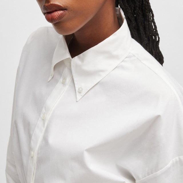 Womens HUGO Evesia Relaxed-fit blouse with contrast branded waistband in white.A voluminous blouse in a modern cropped length by HUGO. Crafted in soft poplin  this piece has a stacked logo on the contrasting elasticated waistband. This product is partly made with organic cotton.- Relaxed fit- Point collar- Long sleeves- Button cuffs- Short length- Back pleat detail to add volume- Contrast elastic waistband with tonal stacked logo- Main material: 100% Cotton.  Machine washable.- Ref: 50518040-100