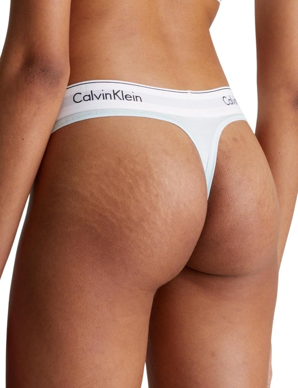 Calvin Klein Modern Cotton Thong Ladies, say goodbye to uncomfortable and unflattering lingerie and hello to the Calvin Klein Modern Cotton thong. Its low-rise fit and minimal rear coverage make it discreet yet fashionably versatile, ideal for any look or occasion. Crafted from a breathable cotton blend, this thong promises day-long comfort, blending seamlessly under any outfit with its sleek, opaque design. Adorned with the iconic Calvin Klein logo waistband, it assures a luxe feel while ensuring a perfect fit. Ideal for complementing with other pieces from Calvin Klein's lingerie line, it's a must-have for those prioritising comfort without compromising on style. Elevate your lingerie collection with this essential piece – your go-to for confidence and elegance every day.