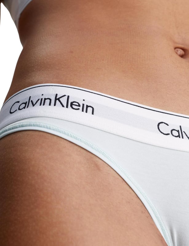 Calvin Klein Modern Cotton Thong Ladies, say goodbye to uncomfortable and unflattering lingerie and hello to the Calvin Klein Modern Cotton thong. Its low-rise fit and minimal rear coverage make it discreet yet fashionably versatile, ideal for any look or occasion. Crafted from a breathable cotton blend, this thong promises day-long comfort, blending seamlessly under any outfit with its sleek, opaque design. Adorned with the iconic Calvin Klein logo waistband, it assures a luxe feel while ensuring a perfect fit. Ideal for complementing with other pieces from Calvin Klein's lingerie line, it's a must-have for those prioritising comfort without compromising on style. Elevate your lingerie collection with this essential piece – your go-to for confidence and elegance every day.