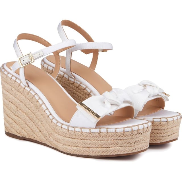 These Gia Bow platform wedges are beautiful, stylish summer sandals to elevate your outfit to new heights. Featuring a strappy white upper with a delicate buckle closure and ankle strap for a perfect, elegant fit. The gorgeous Ted Baker branded gold metal bow adds a touch of glam and the espadrille wedge sole a generous lift to your ensemble.