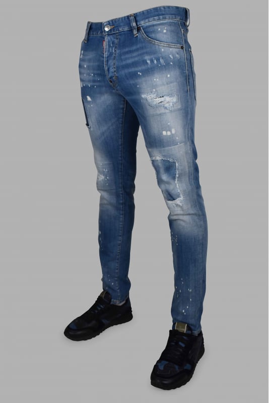 Vaqueros Dsquared2 Cool Guy de algodón azul.Efecto lavado y distressed.Manchas de pintura blanca.Ligeras roturas.Etiqueta roja con logotipo en la bragueta.Parche trasero marrón con palmeras y letras rojas.Cierre con botones.Trabillas.Cinco bolsillos, 2 de ellos traseros.Corte recto.