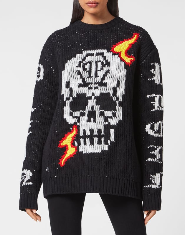 Un jersey liso de cuello redondo también puede transmitir estilo y distinción. Como esta versión de lana de cordero de punto elástico con las icónicas incrustaciones de calaveras y las letras de la marca. Dobladillos de punto de canalé.