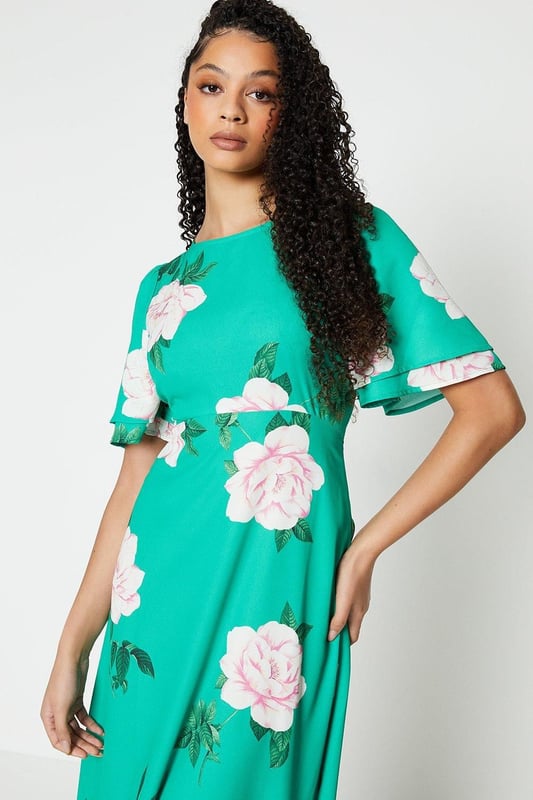Vibrant floral print adorns this woven midi dress
Flattering round neckline and flutter sleeves
Relaxed fit through the bodice
Midi length hits below the knee
woven fabric with a lightweight feel

Embrace the season's botanical trend with this eye-catching floral midi dress. The vibrant print and flutter sleeves exude a feminine charm, perfect for daytime occasions like brunches or family gatherings. Style it with trainers or sandals for a relaxed yet polished look that transitions seamlessly from day to night.