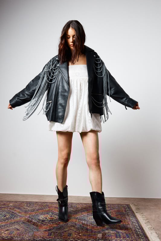 Genuine leather jacket with striking pearl trim detailing draped across the shoulders and back
        Classic biker silhouette with notched lapels and asymmetric zip fastening
        Decorative fringe trim cascading from the pearl embellishments for dramatic movement
        Functional side pockets and adjustable buckle detail at the hem
        Fully lined for comfort and ease of wear
    
    Make a bold statement with this Nasty Gal leather jacket that reimagines the classic biker style with eye-catching pearl trim detailing. The dramatic draping pearl chains and fringe create a captivating silhouette that demands attention, perfect for those who aren't afraid to stand out. Style it as seen with a floaty white mini dress and western-inspired boots for an edgy contrast that works brilliantly for nights out. For a more structured evening look, pair with a fitted bodycon dress and strappy heels. The versatile design allows for both rebellious and refined styling options, making it an ideal choice for everything from gigs and club nights to cocktail bars. This jacket doesn't just complete an outfit-it defines it, bringing undeniable character to your night-out wardrobe.
