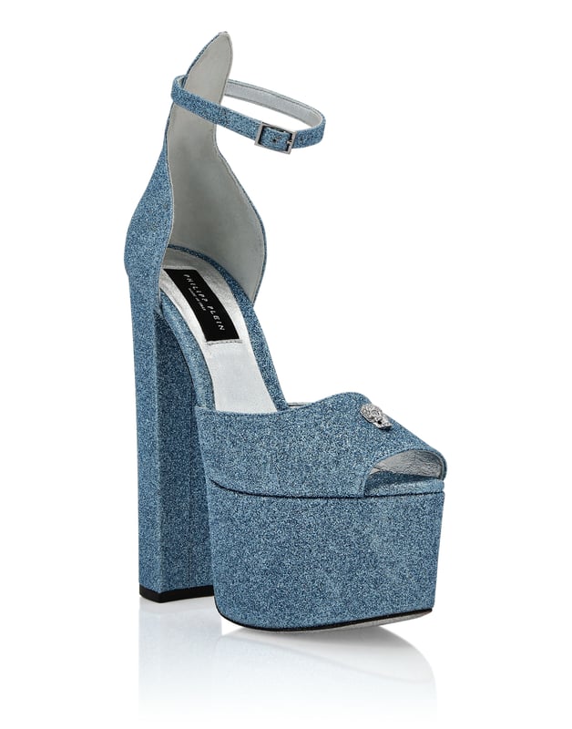 Maak je zomer uniek met deze plateausandalen met open teen... Bekijk de details.   Glitter bovenwerk   Jewel Skull op het bandje   Gesp enkelbandje   12 cm gevoerde hoge blokhakken en 4 cm plateau   Leren zool   Gevoerde binnenkant en voetbed