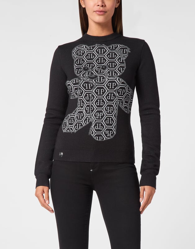 Juguetón y provocativo a la vez, este jersey de osito de peluche con strass transforma un clásico acogedor en una atrevida declaración de moda con un toque brillante y descarado.   Diseño de osito de peluche con adornos de cristal para un brillo destacado.   Mezcla de punto suave para aportar calidez con un toque de elasticidad.   Corte entallado que realza una silueta elegante y femenina.   Puños y bajo acanalados para un acabado refinado.   Combina sin esfuerzo con vaqueros de cintura alta o faldas de cuero.