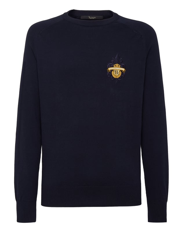 Este sofisticado jersey de cuello redondo combina a la perfección la comodidad con una elegancia discreta, lo que lo convierte en un básico versátil tanto para looks informales como elevados. Su confección de primera calidad garantiza un atractivo atemporal.   Confeccionado en algodón de alta calidad para un tacto suave y transpirable.   Presenta un sutil pero refinado escudo bordado que le da un toque de lujo.   Puños y dobladillo acanalados para un acabado elegante y a medida.    Ideal para llevar encima de camisas o solo para un estilo versátil.   Perfecta para combinar con pantalones de sastrería o vaqueros elegantes.
