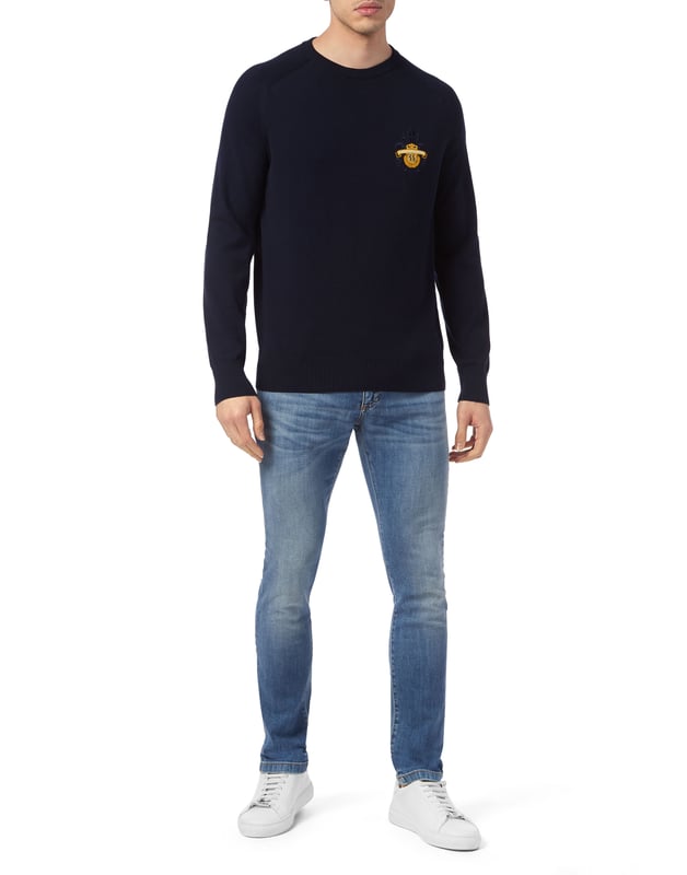 Este sofisticado jersey de cuello redondo combina a la perfección la comodidad con una elegancia discreta, lo que lo convierte en un básico versátil tanto para looks informales como elevados. Su confección de primera calidad garantiza un atractivo atemporal.   Confeccionado en algodón de alta calidad para un tacto suave y transpirable.   Presenta un sutil pero refinado escudo bordado que le da un toque de lujo.   Puños y dobladillo acanalados para un acabado elegante y a medida.    Ideal para llevar encima de camisas o solo para un estilo versátil.   Perfecta para combinar con pantalones de sastrería o vaqueros elegantes.
