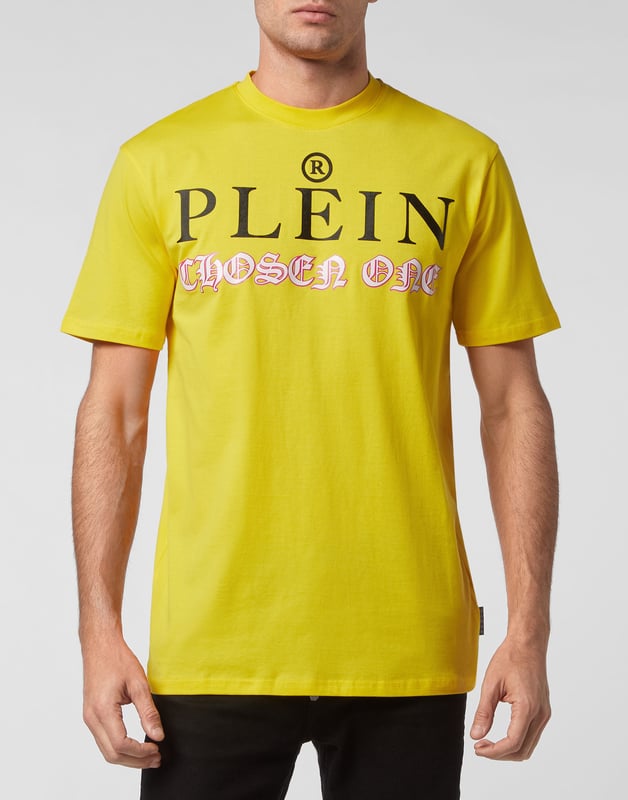 Mire cómo se transforma esta camiseta de jersey de algodón con cuello redondo. La prenda lleva el icónico estampado de las letras de la marca y una frase irónica al más puro estilo Plein. Un parche de cuero saffiano con el Hexágono PP está cosido en el canesú. Dobladillos de pespunte doble.