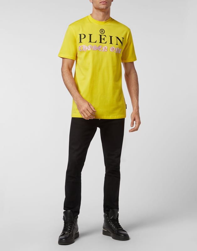 Mire cómo se transforma esta camiseta de jersey de algodón con cuello redondo. La prenda lleva el icónico estampado de las letras de la marca y una frase irónica al más puro estilo Plein. Un parche de cuero saffiano con el Hexágono PP está cosido en el canesú. Dobladillos de pespunte doble.