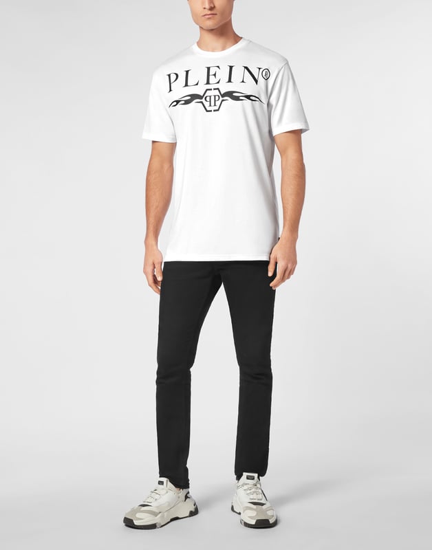Bold and unapologetic, this round neck t-shirt channels street-luxe energy with graphic flames and signature logo detailing ,  a must-have for statement layering.   Crafted from premium cotton for elevated comfort.   Bold logo and flame artwork create visual impact.   Classic fit ideal for everyday styling.   Hexagon emblem adds a touch of brand identity.   Pairs effortlessly with denim, joggers, or layered under a jacket.