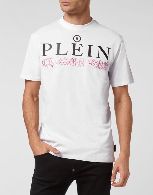 Mire cómo se transforma esta camiseta de jersey de algodón con cuello redondo. La prenda lleva el icónico estampado de las letras de la marca y una frase irónica al más puro estilo Plein. Un parche de cuero saffiano con el Hexágono PP está cosido en el canesú. Dobladillos de pespunte doble.