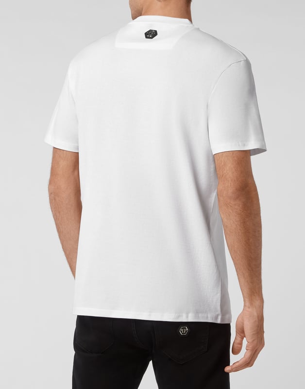 Mire cómo se transforma esta camiseta de jersey de algodón con cuello redondo. La prenda lleva el icónico estampado de las letras de la marca y una frase irónica al más puro estilo Plein. Un parche de cuero saffiano con el Hexágono PP está cosido en el canesú. Dobladillos de pespunte doble.