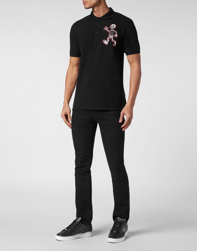 Ontdek de originaliteit van deze polo met korte mouwen, gemaakt van katoen piqué en versierd met origineel borduurwerk.   Katoen piqué   PP Hexagon op een saffiaan lederen patch genaaid op de linkerborst samen met een geborduurde patch van Skeleton, de nieuwe mascotte van dit seizoen   Gothic-stijl Merkopdruk en geborduurd op de rug   Knopen met logo   Chevron ribgebreide kraag en manchetten   Twee zijsplitten
