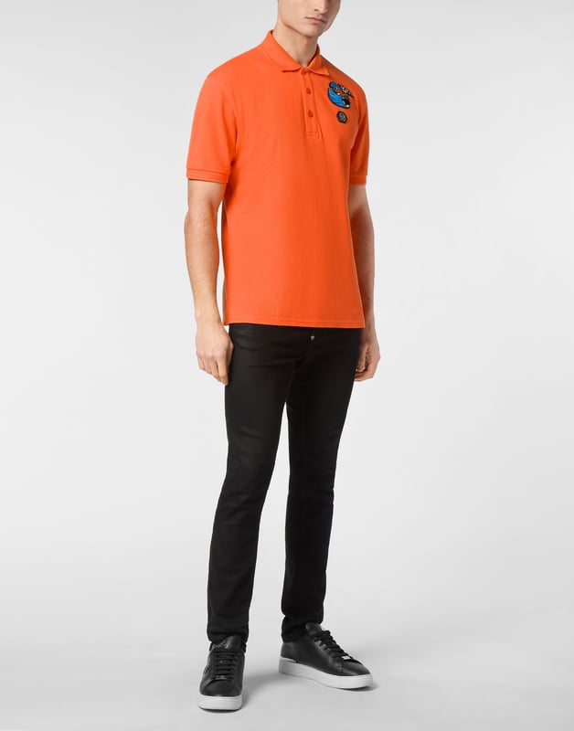 Discover the originality of this cotton piqué short sleeve polo shirt decorated with the Brand’s iconic elements.   Cotton piqué   Embroidered patch   Logoed patch sewn at left chest   Logoed buttons   Rib knit collar and cuffs    Two side slits