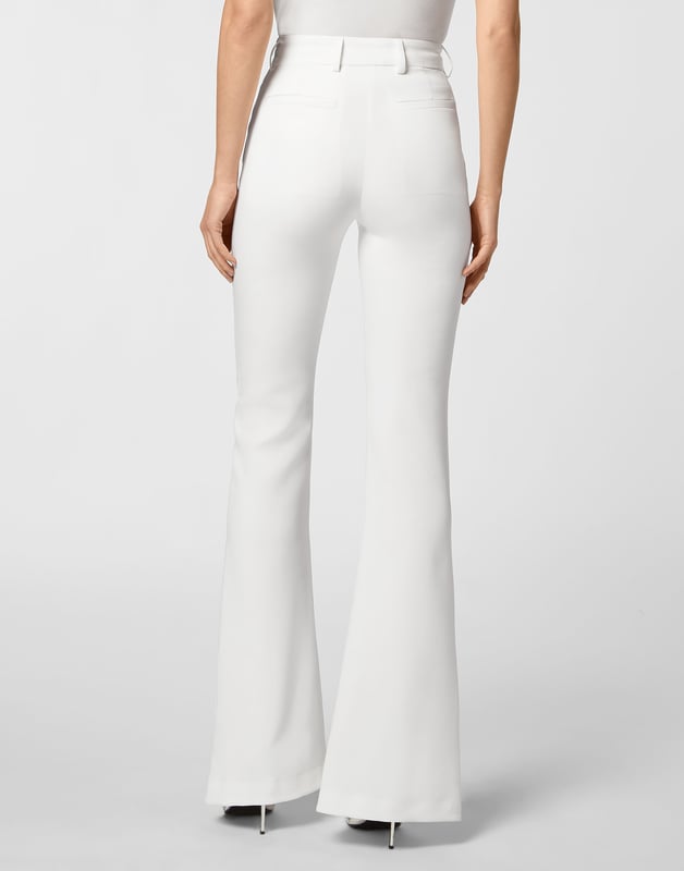 Pantalones de cintura alta de poliéster elástico, presentan abertura frontal en la parte inferior. Cintura con tachuelas y botones. Bolsillos de ranura.