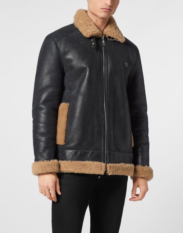 Discover the style of Plein with this sheepskin jacket. Check out its distinctive details.   Sheepskin with fur trim finish   Schafsfell shirt collar with two leather straps   Schafsfell Skull&Bones on the back   PP Hexagon Logo on a saffian leather patch sewn at left chest   Zip fastener   Two slit pockets with stitched outline   Two side straps on bottom hem   Unlined