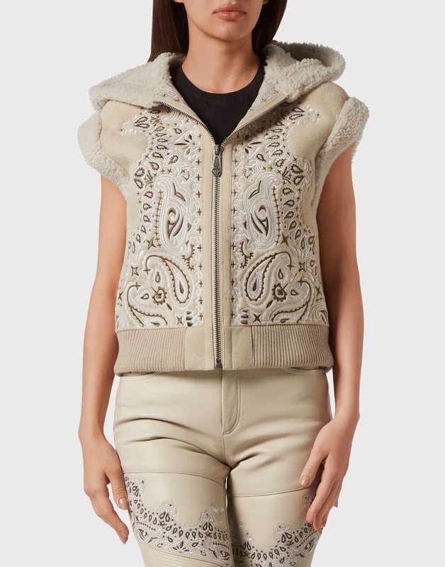 Descubre el estilo de Plein con esta chaqueta sin mangas con capucha de borreguillo. Echa un vistazo a sus distintivos detalles Paisley Bandanna.   Piel de oveja bordada con estampado Paisley estilo Bandana.   La icónica calavera bordada en la espalda   Cierre de cremallera   Dos bolsillos con aberturas   Acabado con ribete de piel   Dobladillo inferior de punto elástico