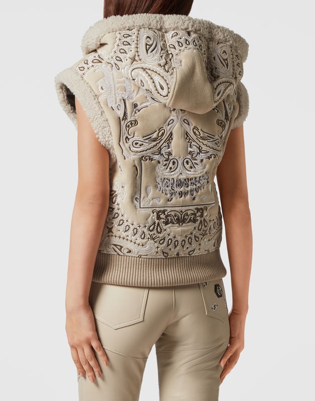 Descubre el estilo de Plein con esta chaqueta sin mangas con capucha de borreguillo. Echa un vistazo a sus distintivos detalles Paisley Bandanna.   Piel de oveja bordada con estampado Paisley estilo Bandana.   La icónica calavera bordada en la espalda   Cierre de cremallera   Dos bolsillos con aberturas   Acabado con ribete de piel   Dobladillo inferior de punto elástico