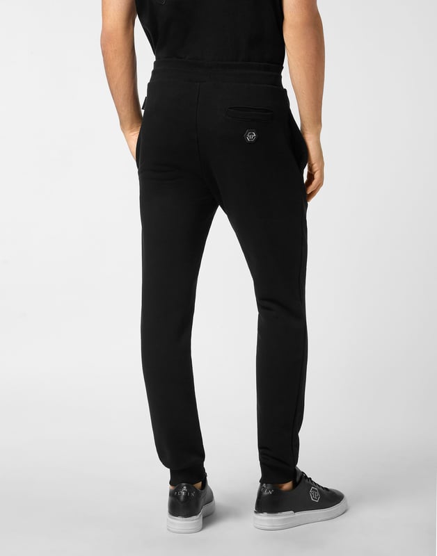 Entdecken Sie die Originalität dieser Jogginghose aus gemischtem Baumwollfleece, die mit einzigartigen Details verziert ist.   Baumwoll-Fleece-Mischung   Aufgedrucktes Muster am linken Bein   Gestickter Aufnäher auf dem linken Bein   Aufnäher mit Logo   Schlitztaschen   Rippenstrickbund mit Stopp-Kordelzug   Rippstrickbündchen
