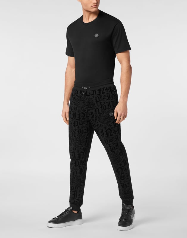 Entdecken Sie die Originalität dieser Jogginghose mit Jacquard-Muster.   Baumwollmischgewebe mit allover beflocktem Muster   Aufnäher mit Logo   Schlitztaschen   Gerippter Bund mit Stopp-Kordelzug   Rippstrickbündchen