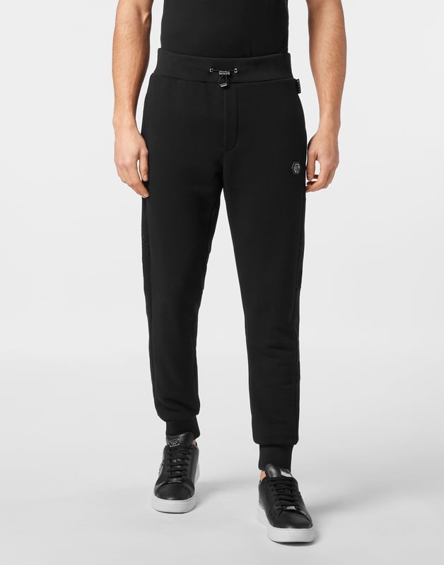 Entdecken Sie die Originalität dieser Jogginghose aus Baumwollfleece, die mit einzigartigen Details verziert ist.   Baumwollfleece-Mischung   Stoffeinsätze mit Kristallapplikationen   Aufnäher mit Logo   Schlitztaschen   Gerippter Bund mit Stopp-Kordelzug   Rippstrickbündchen