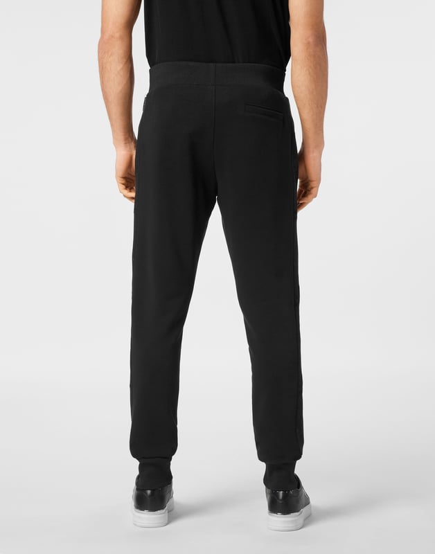 Entdecken Sie die Originalität dieser Jogginghose aus Baumwollfleece, die mit einzigartigen Details verziert ist.   Baumwollfleece-Mischung   Stoffeinsätze mit Kristallapplikationen   Aufnäher mit Logo   Schlitztaschen   Gerippter Bund mit Stopp-Kordelzug   Rippstrickbündchen