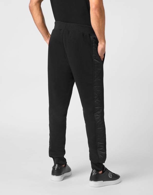 Entdecken Sie die Originalität dieser Jogginghose aus Baumwollfleece, die mit einzigartigen Nähten verziert ist.   Baumwoll-Fleece-Mischung   Gepolsterte Nylondetails   PP Hexagon Logo auf einem Lederabzeichen aus Safran auf dem linken Bein   Schlitztaschen   Gerippter Bund mit Stoppkordelzug   Rippstrickbündchen