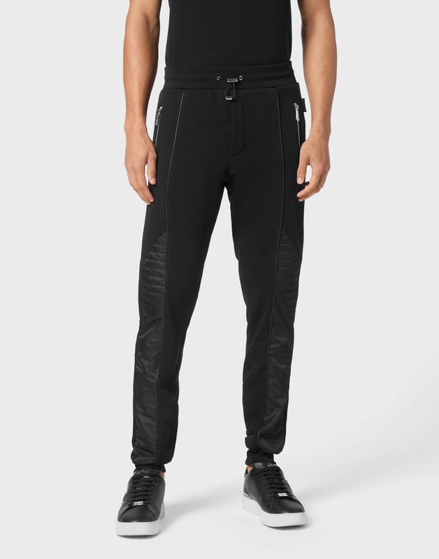 Descubra la originalidad de estos pantalones de chándal de forro polar de mezcla de algodón decorados con costuras únicas.   Vellón de mezcla de algodón   Detalles de nailon acolchado   Hexágono de PP en una insignia de cuero saffiano cosida en la espalda   Bolsillos abiertos con cremallera   Cintura de punto elástico con cordón de tope   Puños de punto elástico