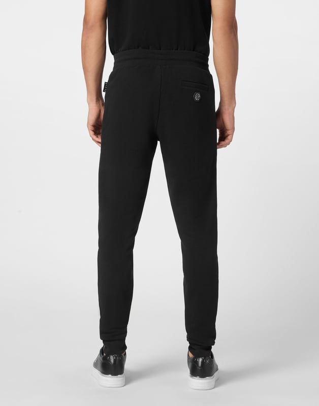 Descubra la originalidad de estos pantalones de chándal de forro polar de mezcla de algodón decorados con costuras únicas.   Vellón de mezcla de algodón   Detalles de nailon acolchado   Hexágono de PP en una insignia de cuero saffiano cosida en la espalda   Bolsillos abiertos con cremallera   Cintura de punto elástico con cordón de tope   Puños de punto elástico