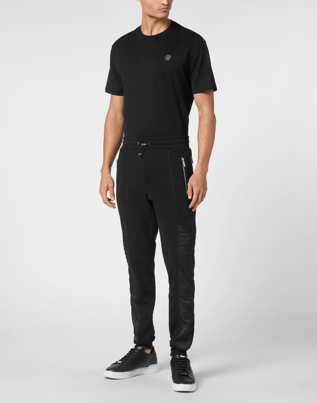Descubra la originalidad de estos pantalones de chándal de forro polar de mezcla de algodón decorados con costuras únicas.   Vellón de mezcla de algodón   Detalles de nailon acolchado   Hexágono de PP en una insignia de cuero saffiano cosida en la espalda   Bolsillos abiertos con cremallera   Cintura de punto elástico con cordón de tope   Puños de punto elástico