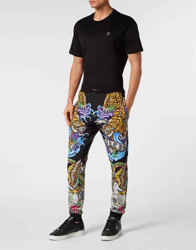 Si lo suyo son los conjuntos deportivos con un toque de personalidad, eche un vistazo a estos pantalones de chándal de forro polar de mezcla de algodón.   Suave forro polar de mezcla de algodón   Decoraciones estampadas con efecto tatuaje    Hexágono de PP en una insignia de cuero saffiano cosida en el lado izquierdo   Bolsillos con aberturas   Cintura parcialmente de nailon elástico con cordón de tope   Puños de punto elástico