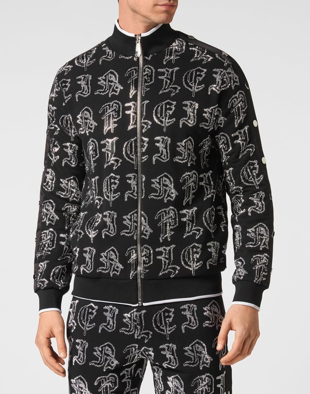 Elija correr con estilo con la singularidad que identifica el estilo de Plein. Hemos diseñado este chándal de forro polar de algodón elástico con pedrería.   Forro polar de algodón con letras de pedrería de estilo gótico.   Pantalón y parte superior con botones laterales de color en contraste    Cierre de cremallera   Bolsillos con aberturas   Cintura con cordón de ajuste de tope   Dobladillos con remates de punto elástico