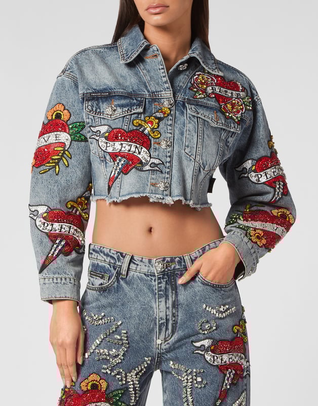 Verfraaid  Draag de stijl van Plein met dit kostbare denim crop jack met de thema-elementen van dit seizoen. Bekijk de kenmerkende details.   Steengewassen denim   Met rijnen versierde patches met Love Tattoo-thema   Metalen juwelenknopen   Twee opgestikte zakken met klep   Ruw gesneden onderboord