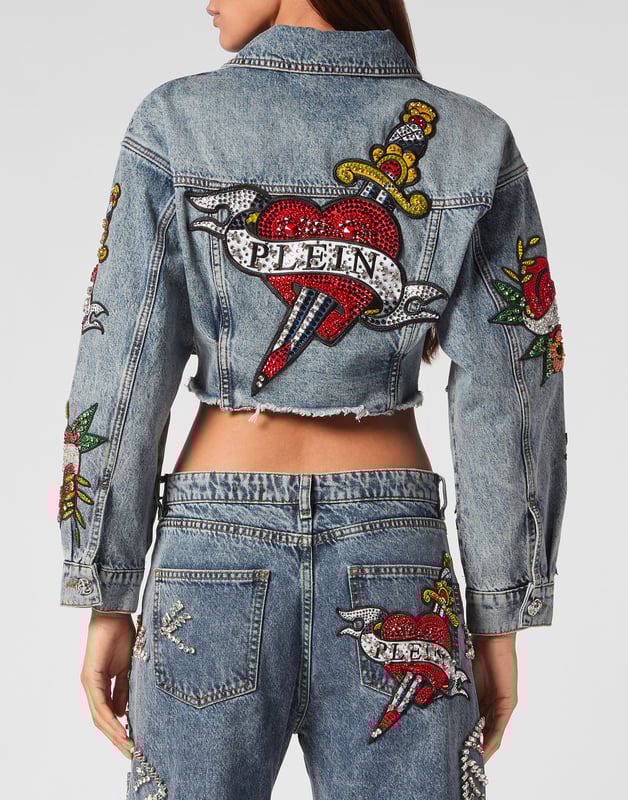 Verfraaid  Draag de stijl van Plein met dit kostbare denim crop jack met de thema-elementen van dit seizoen. Bekijk de kenmerkende details.   Steengewassen denim   Met rijnen versierde patches met Love Tattoo-thema   Metalen juwelenknopen   Twee opgestikte zakken met klep   Ruw gesneden onderboord