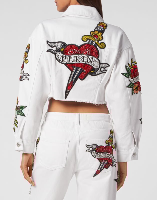 mit Schmucksteinen  Tragen Sie den Stil von Plein mit dieser edlen Jeans-Crop-Jacke mit den Themenelementen dieser Saison. Sehen Sie sich die markanten Details an.   Mit Stein gewaschener Denim    Strassbesetzte Aufnäher im Love-Tattoo-Stil   Metall-Juwelenknöpfe   Zwei aufgesetzte Taschen mit Klappe   Ungeschnittener unterer Saum