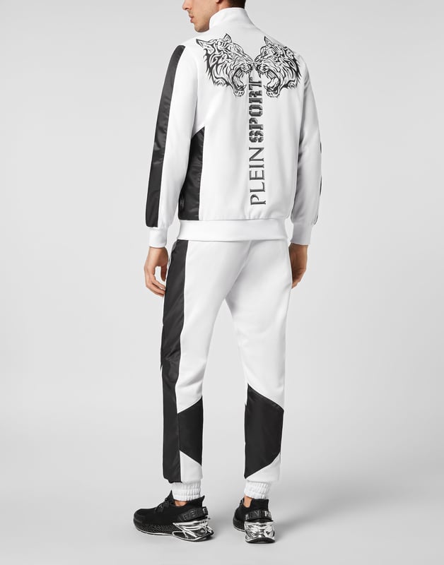 Entdecke den neuen Trainingsanzug, mit dem du beim Sport und in der Freizeit glänzen kannst.   Handliches und widerstandsfähiges Triacetat   Unifarbene Nylon-Einsätze   Tiger- und Brand-Prints auf der Rückseite der Jacke   Gummierter Aufnäher mit dem Brand-Symbol auf Jacke und Hose genäht   Wasserdichter Reißverschluss an der Jacke   Schlitztaschen   Bund mit Kordelzug   Rippstrickbündchen