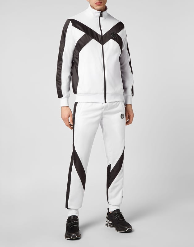 Entdecke den neuen Trainingsanzug, mit dem du beim Sport und in der Freizeit glänzen kannst.   Handliches und widerstandsfähiges Triacetat   Unifarbene Nylon-Einsätze   Tiger- und Brand-Prints auf der Rückseite der Jacke   Gummierter Aufnäher mit dem Brand-Symbol auf Jacke und Hose genäht   Wasserdichter Reißverschluss an der Jacke   Schlitztaschen   Bund mit Kordelzug   Rippstrickbündchen