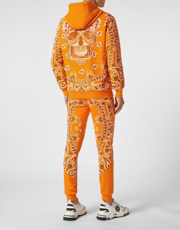Für Ihren perfekten Laufstil haben wir diesen Trainingsanzug aus Baumwollfleece mit den kultigen Totenkopf- und Paisley-Dekoren entworfen.   Weiches Baumwollfleece im Bandanna-Stil mit Paisley-Print   Der ikonische strassbesetzte Skull-Print auf dem Rücken  PP-Sechseck auf einem Abzeichen aus Saffianleder auf Jacke und Hose   Kapuzenpulli mit Reißverschluss   Schlitztaschen   Bund mit Stopp-Kordelzug   Rippstrickbündchen "