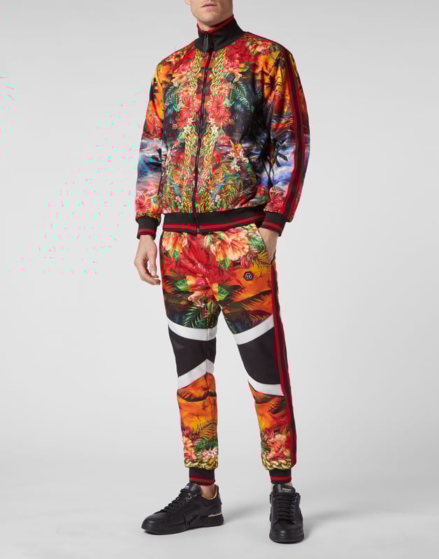 Choose to jog in style with the uniqueness identifying the style of Plein. We designed this techno fabric tracksuit featuring a Hawaii-themed print throughout.   Hawaii-inspired print triacetate   Contrasting sidebands on sleeves and outseam   Zip-up sweatjacket with PP Hexagon on a saffian leather patch sewn at left chest   Two slit pockets   PP Hexagon on a saffian leather badge sewn on the left side of pants   Slit pockets   Waistband with stop-cord drawstring   Rib knit hems