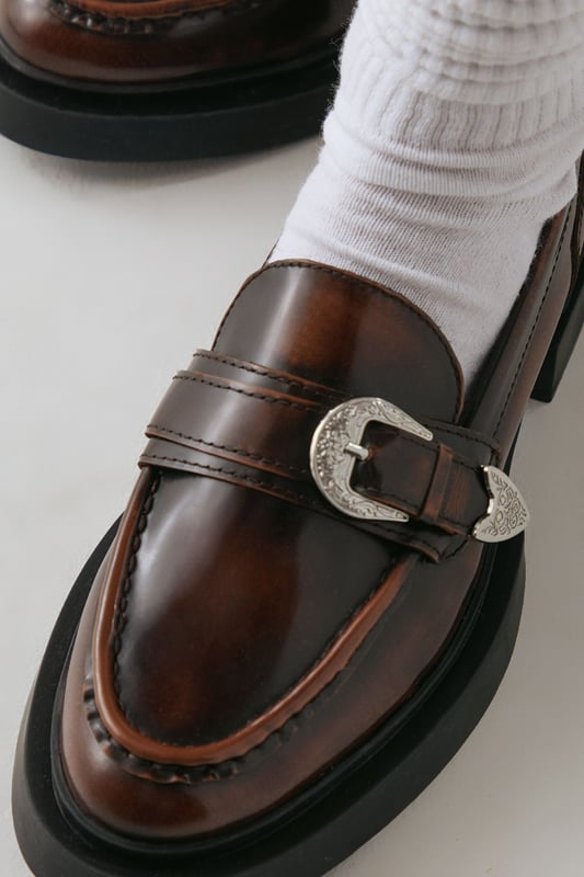 Genuine leather upper for durability and style
        Western-inspired buckle detail adds a unique touch
        Chunky sole provides comfort and a trendy look
        Flat heel (0-2cm) ensures all-day wearability
        Versatile loafer design suitable for various occasions
    
    Step out in confidence with these Faith for Warehouse leather loafers. The western buckle detail adds a dash of intrigue to the classic silhouette, while the chunky sole offers both style and substance. Perfect for the fashion-forward woman who values comfort without compromising on style. Pair these versatile flats with tailored trousers and a crisp white shirt for a smart casual look at the office, or team them with a flowing midi dress for weekend brunches. The rich leather upper will develop a beautiful patina over time, making these loafers a cherished addition to your wardrobe. Whether you're navigating city streets or attending casual gatherings, these loafers will keep you looking polished and feeling comfortable all day long.