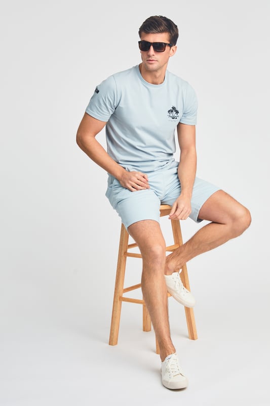The Tokyo Laundry Logo Beach Set features a printed palm tree design on both the t-shirt and jogger shorts. Ideal for summer holidays, this comfortable, lightweight set is perfect for beach days and warm-weather adventures. A stylish and relaxed choice for your summer wardrobe.