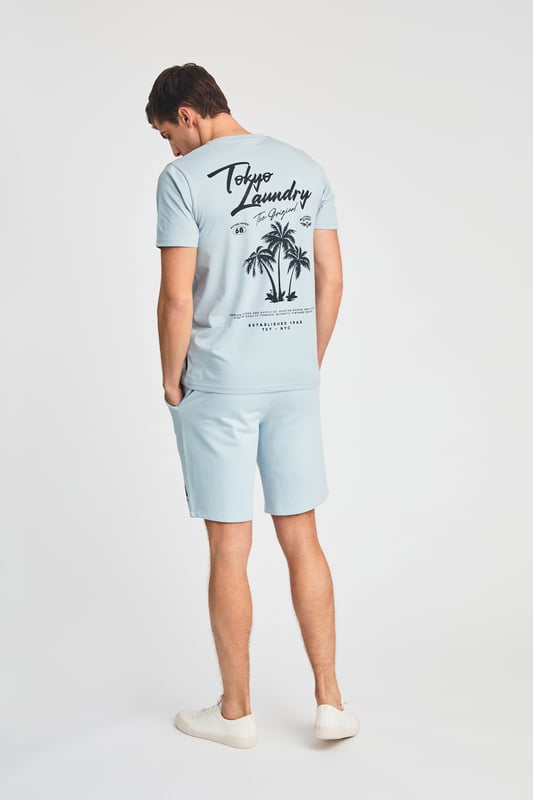 The Tokyo Laundry Logo Beach Set features a printed palm tree design on both the t-shirt and jogger shorts. Ideal for summer holidays, this comfortable, lightweight set is perfect for beach days and warm-weather adventures. A stylish and relaxed choice for your summer wardrobe.