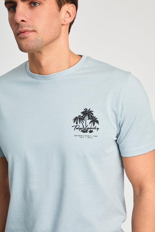 The Tokyo Laundry Logo Beach Set features a printed palm tree design on both the t-shirt and jogger shorts. Ideal for summer holidays, this comfortable, lightweight set is perfect for beach days and warm-weather adventures. A stylish and relaxed choice for your summer wardrobe.