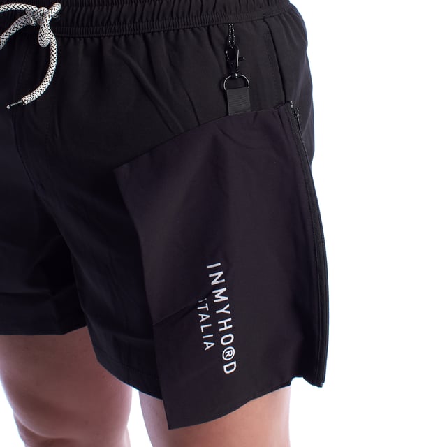Bañador de hombre inMyHood Italia.\n\nEste bañador corto de InMyHood Italia está pensado para quienes priorizan la comodidad, el estilo moderno y la funcionalidad en cada detalle. Ideal tanto para días de playa como para looks relajados de verano.\n\nDetalles:\n- Diseño minimalista y versátil.\n- Cintura elástica ajustable con cordón.\n- Forro interior de malla.\n- Tejido técnico de secado rápido.\n- Bolsillos laterales.\n- Bolsillo exterior con cremallera y mosquetón para enganchar al bañador.\n- Bolsillo trasero con cierre de cremallera.\n- Etiqueta distintiva.\n\nUna prenda ideal para quienes valoran el equilibrio entre estilo y funcionalidad. Este bañador hombre de Inmyhood ofrece libertad de movimiento, materiales cómodos y un diseño urbano que destaca en cualquier entorno.\n Composición: 95% Poliéster, 5% Elastano\n Cuidados:\nLavar a mano o a máquina en ciclo suave, máximo 30 °C.\nNo usar lejía ni productos blanqueadores.\nNo usar secadora; secar al aire libre, preferiblemente a la sombra.\nNo planchar.