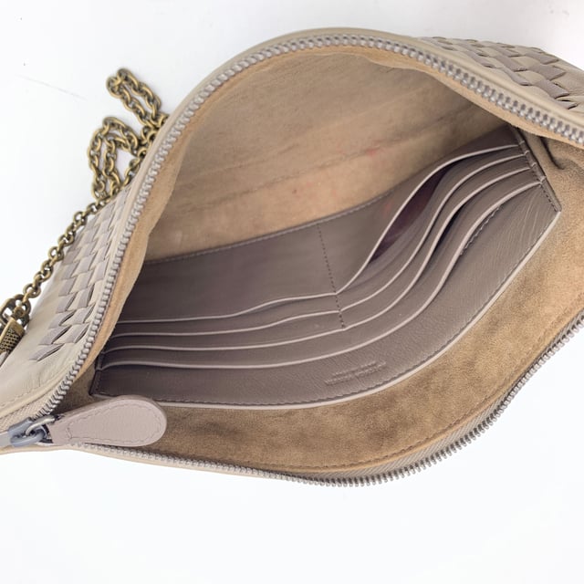 VINTAGE, RRP AS NEW
Elegant in its simplicity and rich in texture, this Bottega Veneta taupe leather zip pouch bag is a refined expression of the house's iconic craftsmanship. The front features Bottega's signature Intrecciato woven leather, a tactile nod to artisanal tradition, contrasted beautifully by the smooth leather body.  The bag opens with a sleek upper zipper closure, revealing a plush brown suede interior thoughtfully designed with six open side pockets and one larger slip pocket-perfectly organized for essentials. A removable gold-tone chain strap adds a touch of versatility and understated glamour.  Inside, the 'Bottega Veneta - Made in Italy' engraving stands as a quiet testament to its heritage-proof that timeless design never shouts, it whispers. Condition Rating: A - EXCELLENTCondition Details: Some light scratches on leather due to normal use. Please check the photos carefully and ask if you need to know more details or if you have any doubts.Measurements (cm):Depth: 2.5Height: 15.2Length: 24.1Other Details: Dustbag? YesKeys? NoBox? No Measurments:  width: 25 mm length: 241 mm height: 152 mm