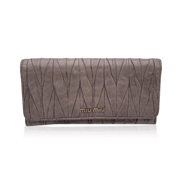 VINTAGE, RRP WIE NEU  
Elegant und mit einem Hauch von Kante, ist dieses Miu Miu Continental Wallet ein verfeinerter Klassiker, eingehüllt in taupefarbenes Matelassé-Leder mit einem subtilen, abgenutzten Effekt, der genau den richtigen Charakter zu seiner eleganten Silhouette hinzufügt. Das ikonische goldene MIU MIU-Logo glänzt auf dem Verschluss, der mit einem dezenten Knopf gesichert ist. Öffnen Sie es, um ein durchdacht gestaltetes Inneres zu enthüllen: 12 Kreditkartenfächer, zwei geräumige Fächer, ein Münzfach mit Reißverschluss und eine seitliche offene Sektion, die ordentlich unter dem Verschluss verborgen ist. Innen ist 'MIU MIU' in das Leder eingeprägt, mit einer Seriennummer, die als leise Markierung der Authentizität dient. Unaufdringlich und endlos schick, ist dieses Stück mehr als nur eine Geldbörse – es ist ein kleines Stück von Miu Mius verspielter Eleganz, das dazu gemacht ist, getragen und geschätzt zu werden.  
Zustandsbewertung: B - SEHR GUTER ZUSTAND  
Zustandsdetails: Sanft gebraucht. Einige leichte Kratzer auf dem Leder aufgrund normalen Gebrauchs. Miu Miu-Box enthalten. Bitte überprüfen Sie die Fotos sorgfältig und fragen Sie, wenn Sie mehr Details wissen möchten oder Zweifel haben.  
Maße (cm): Höhe: 10,2 Länge: 19,1  
Box?: Ja  
Maße: Länge: 191 mm Höhe: 102 mm
