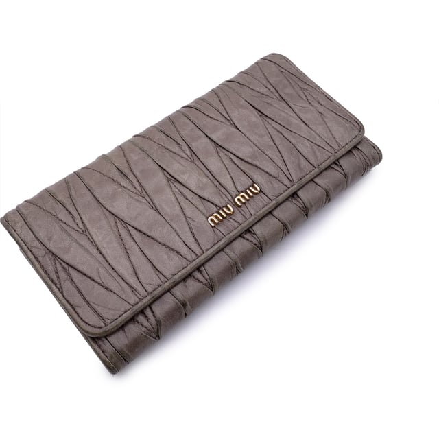 VINTAGE, RRP WIE NEU  
Elegant und mit einem Hauch von Kante, ist dieses Miu Miu Continental Wallet ein verfeinerter Klassiker, eingehüllt in taupefarbenes Matelassé-Leder mit einem subtilen, abgenutzten Effekt, der genau den richtigen Charakter zu seiner eleganten Silhouette hinzufügt. Das ikonische goldene MIU MIU-Logo glänzt auf dem Verschluss, der mit einem dezenten Knopf gesichert ist. Öffnen Sie es, um ein durchdacht gestaltetes Inneres zu enthüllen: 12 Kreditkartenfächer, zwei geräumige Fächer, ein Münzfach mit Reißverschluss und eine seitliche offene Sektion, die ordentlich unter dem Verschluss verborgen ist. Innen ist 'MIU MIU' in das Leder eingeprägt, mit einer Seriennummer, die als leise Markierung der Authentizität dient. Unaufdringlich und endlos schick, ist dieses Stück mehr als nur eine Geldbörse – es ist ein kleines Stück von Miu Mius verspielter Eleganz, das dazu gemacht ist, getragen und geschätzt zu werden.  
Zustandsbewertung: B - SEHR GUTER ZUSTAND  
Zustandsdetails: Sanft gebraucht. Einige leichte Kratzer auf dem Leder aufgrund normalen Gebrauchs. Miu Miu-Box enthalten. Bitte überprüfen Sie die Fotos sorgfältig und fragen Sie, wenn Sie mehr Details wissen möchten oder Zweifel haben.  
Maße (cm): Höhe: 10,2 Länge: 19,1  
Box?: Ja  
Maße: Länge: 191 mm Höhe: 102 mm