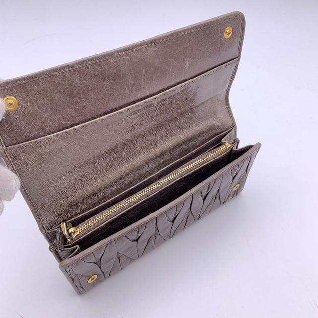 VINTAGE, RRP WIE NEU  
Elegant und mit einem Hauch von Kante, ist dieses Miu Miu Continental Wallet ein verfeinerter Klassiker, eingehüllt in taupefarbenes Matelassé-Leder mit einem subtilen, abgenutzten Effekt, der genau den richtigen Charakter zu seiner eleganten Silhouette hinzufügt. Das ikonische goldene MIU MIU-Logo glänzt auf dem Verschluss, der mit einem dezenten Knopf gesichert ist. Öffnen Sie es, um ein durchdacht gestaltetes Inneres zu enthüllen: 12 Kreditkartenfächer, zwei geräumige Fächer, ein Münzfach mit Reißverschluss und eine seitliche offene Sektion, die ordentlich unter dem Verschluss verborgen ist. Innen ist 'MIU MIU' in das Leder eingeprägt, mit einer Seriennummer, die als leise Markierung der Authentizität dient. Unaufdringlich und endlos schick, ist dieses Stück mehr als nur eine Geldbörse – es ist ein kleines Stück von Miu Mius verspielter Eleganz, das dazu gemacht ist, getragen und geschätzt zu werden.  
Zustandsbewertung: B - SEHR GUTER ZUSTAND  
Zustandsdetails: Sanft gebraucht. Einige leichte Kratzer auf dem Leder aufgrund normalen Gebrauchs. Miu Miu-Box enthalten. Bitte überprüfen Sie die Fotos sorgfältig und fragen Sie, wenn Sie mehr Details wissen möchten oder Zweifel haben.  
Maße (cm): Höhe: 10,2 Länge: 19,1  
Box?: Ja  
Maße: Länge: 191 mm Höhe: 102 mm